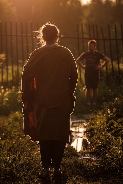 Une fille dans une cape marche le long d'un chemin au coucher du soleil