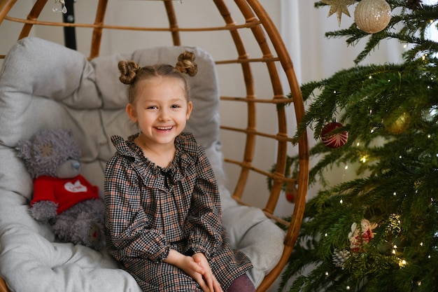 Fille dans une chaise suspendue près de l'arbre de Noël