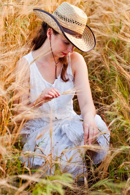 Fille dans un champ de blé en robe blanche et chapeau stetson. Mise au point sélective.