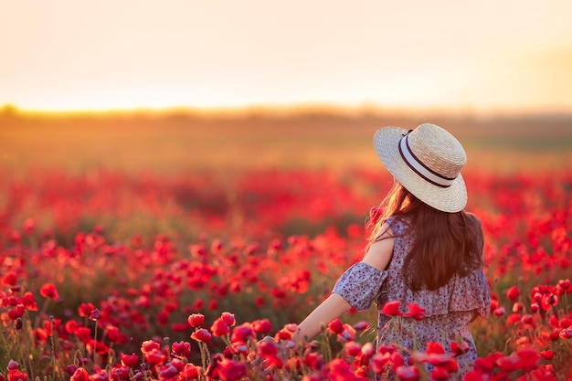 une fille dans un champ avec des coquelicots se tient avec son dos