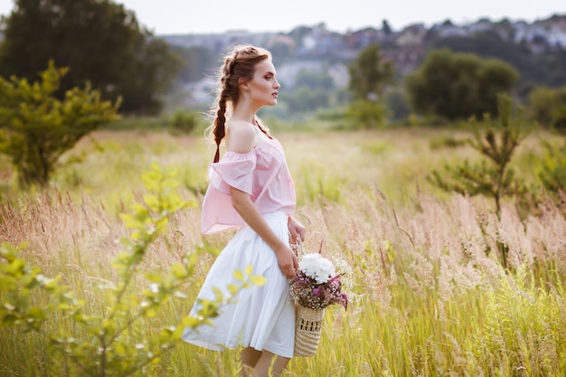 fille dans le champ d'été avec un bouquet