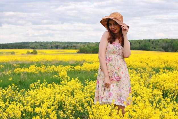 Fille dans un champ de fleurs avec panier et chapeau