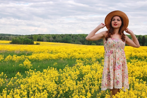 Fille dans un champ de fleurs avec panier et chapeau