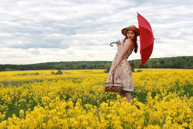 Fille dans un champ de fleurs avec un parapluie et un chapeau