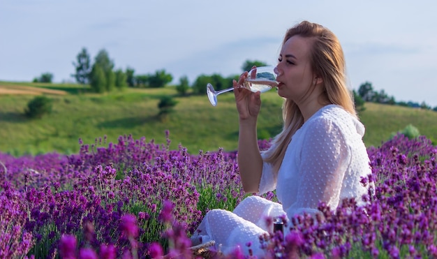 Une fille dans un champ de lavande verse du vin dans un verre