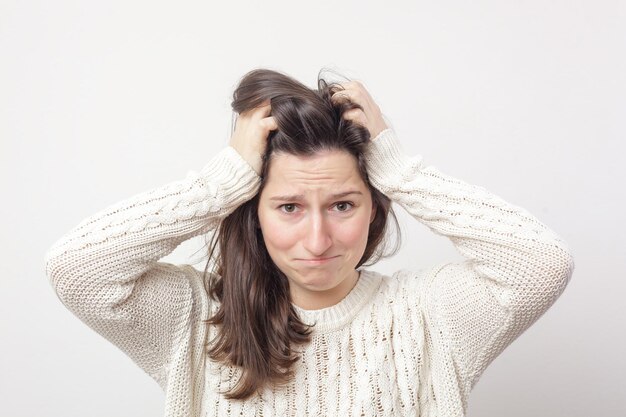 Fille dans un chandail blanc attrape désespérément sa tête à cause du stress et des problèmes