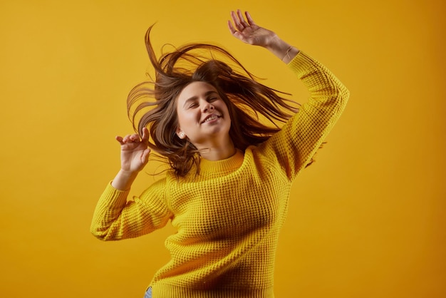 Fille dans un chandail jaune dansant sur fond jaune