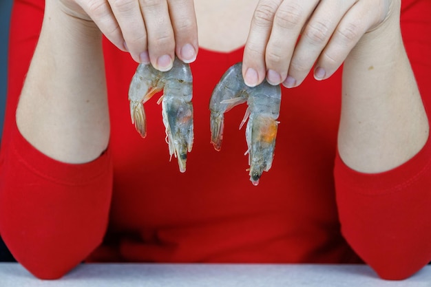 Une fille dans un chandail rouge tient deux crevettes tigrées dans ses mains