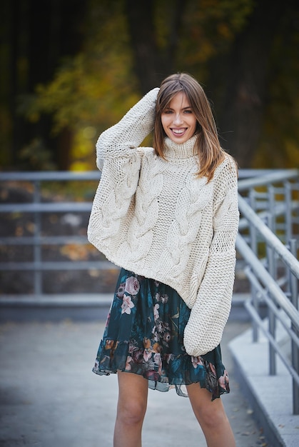 Une fille dans un chandail tricoté gris dans la perspective d'un parc d'automne