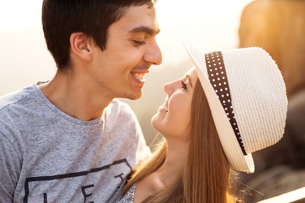 Une fille dans un chapeau élégant en riant et en regardant son petit ami qui sourit également