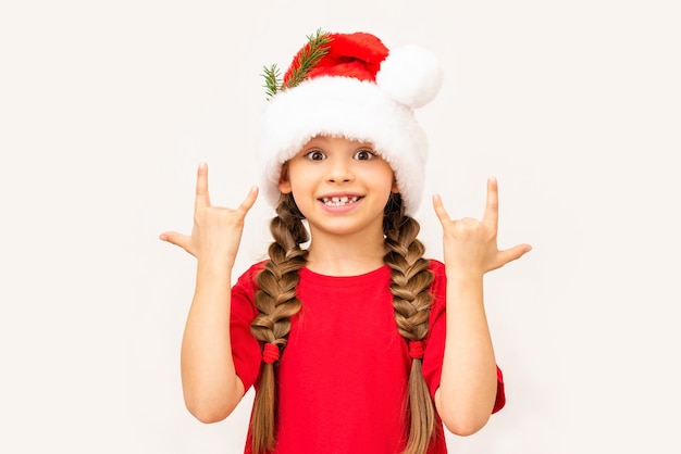 Une fille dans un chapeau de Noël montre ses doigts.