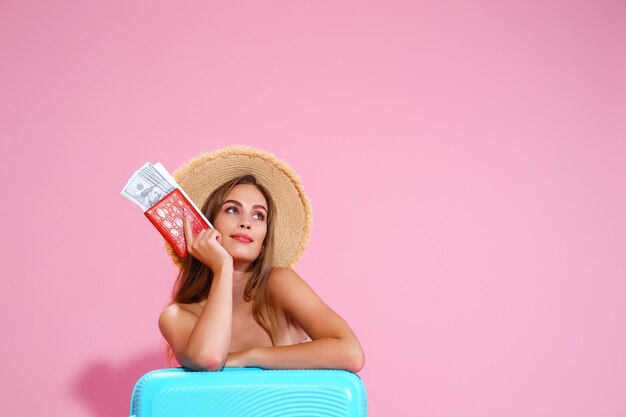 Une fille dans un chapeau de paille tient des billets dans ses mains un voyage un sac