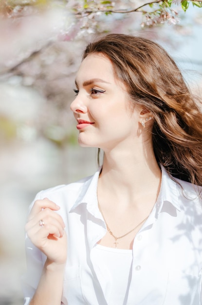 Fille dans une chemise blanche près des arbres de sakura Fleurs de sakura