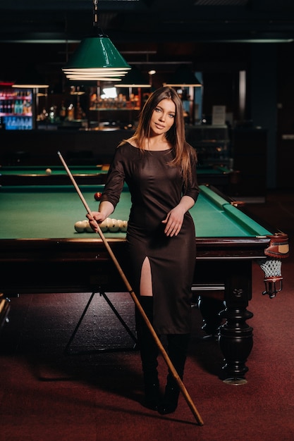 Une fille dans un club de billard avec une queue dans ses mains