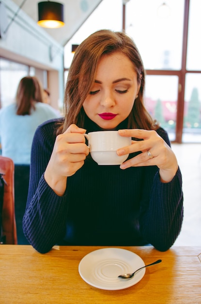 Photo fille dans un col roulé, boire du thé dans un restaurant