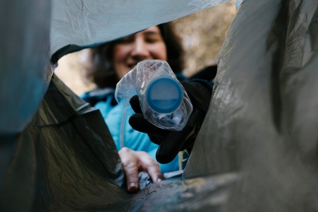 Fille dans une collecte d'ordures déposant une bouteille en plastique dans un sac poubelle photographiée de l'intérieur