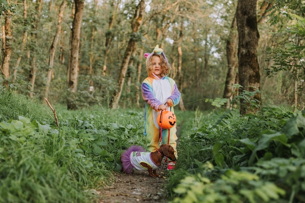 fille dans un costume de kigurumi de licorne arc-en-ciel un chien dans une robe avec une jupe ample Photo de haute qualité