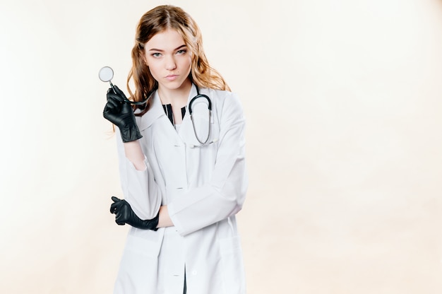 Fille dans un costume de médecin sur un mur monophonique léger