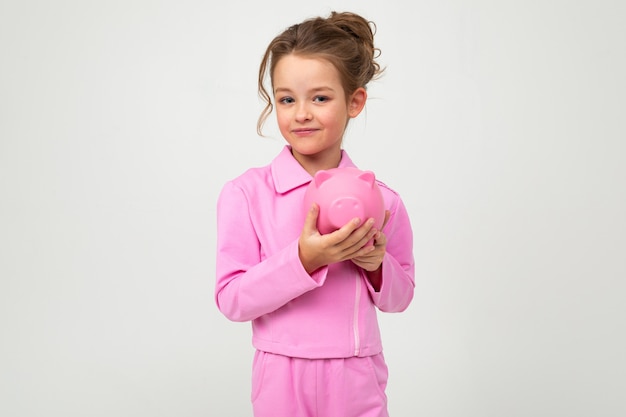 fille dans un costume rose tenant un pot d'argent sur un mur blanc avec un espace vide