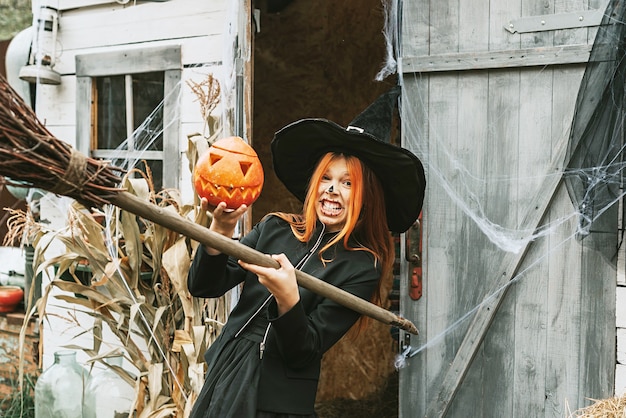 Photo fille dans un costume de sorcière avec un balai lors d'une fête d'halloween