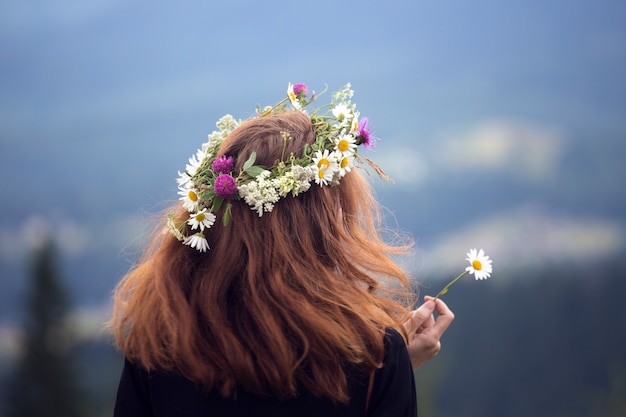 Fille dans une couronne de fleurs sauvages dans les montagnes.