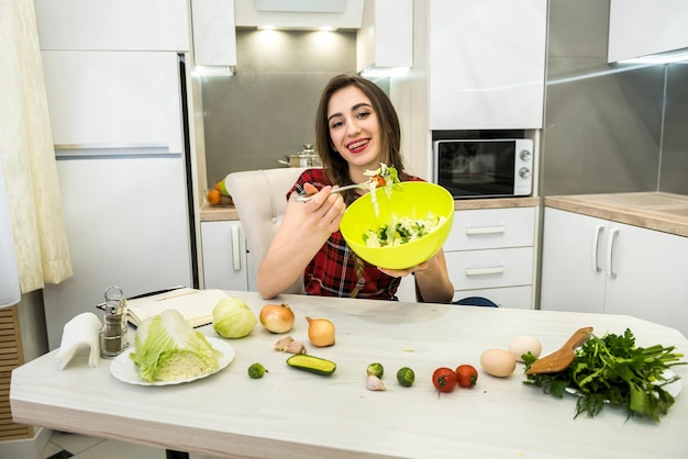 Fille dans la cuisine mangeant une salade de légumes pour un mode de vie sain