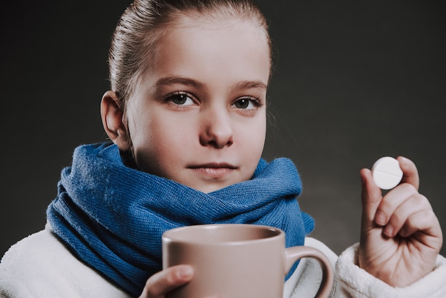 Fille dans l&#39;écharpe tricotée tient la tasse avec boisson chaude et pils.