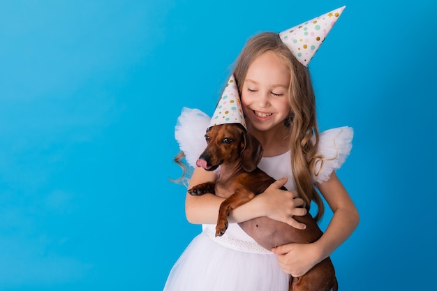 fille dans une élégante robe blanche moelleuse avec un chien teckel dans ses bras