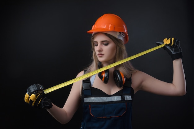 La fille dans une entreprise de construction travaille avec un ruban à mesurer