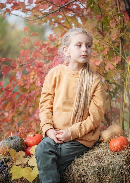 Fille dans le foin avec des citrouilles