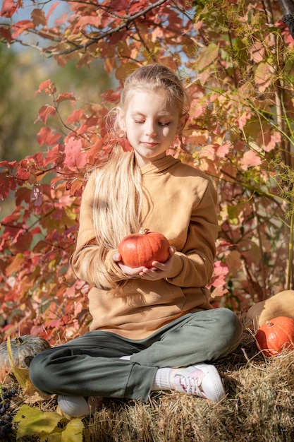 Fille dans le foin avec des citrouilles