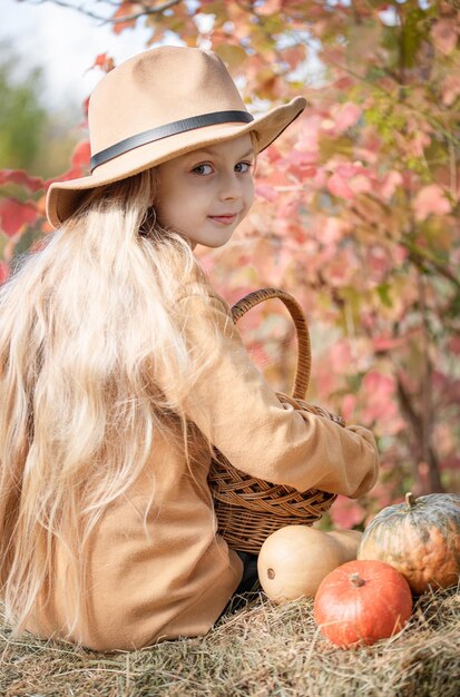 Fille dans le foin avec des citrouilles