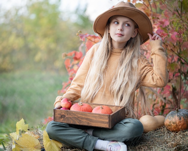 Fille dans le foin avec des citrouilles