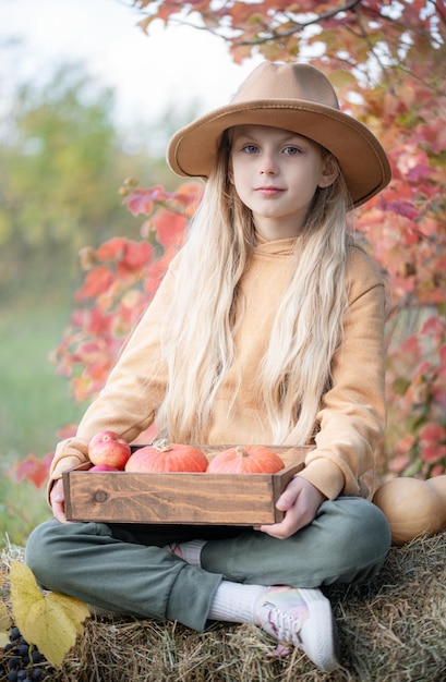 Fille dans le foin avec des citrouilles