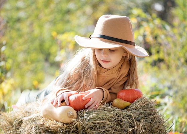 Fille dans le foin avec des citrouilles