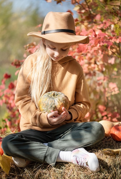 Fille dans le foin avec des citrouilles