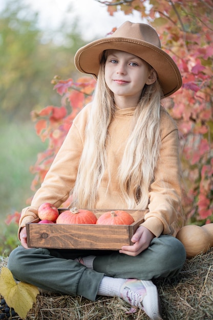 Fille dans le foin avec des citrouilles