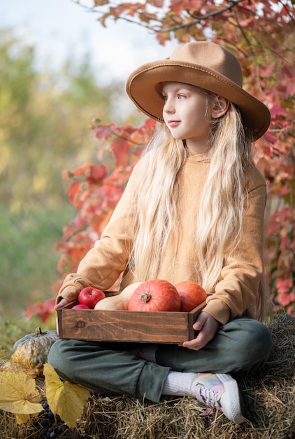 Fille dans le foin avec des citrouilles