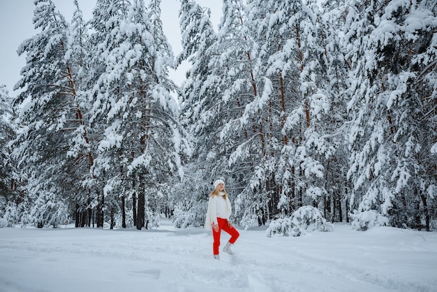 Une fille dans une forêt d'hiver, blonde, une promenade amusante dans la nature