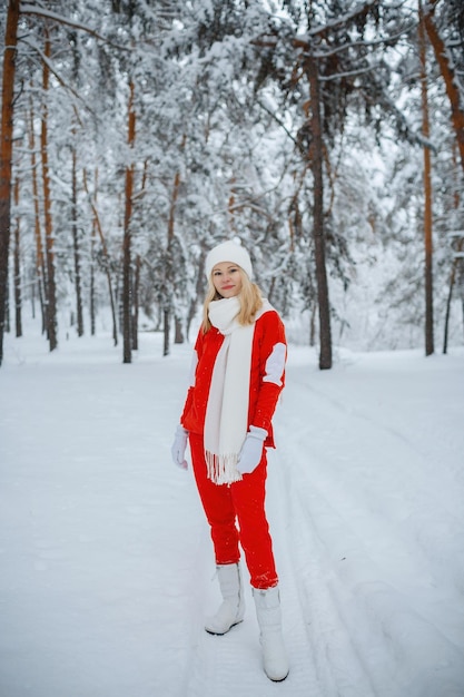 Une fille dans une forêt d'hiver, une blonde en vêtements rouges, une promenade amusante dans la nature