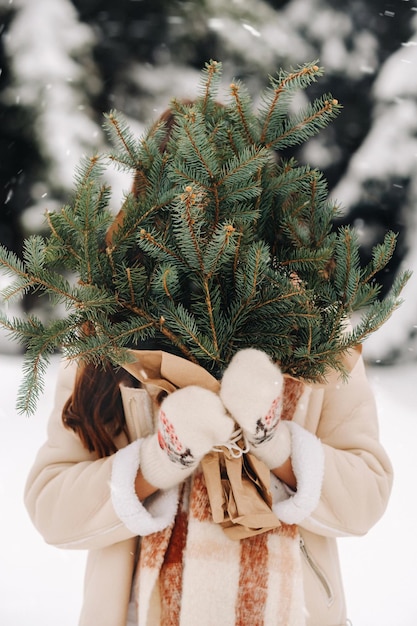 Une fille dans une forêt d'hiver avec un bouquet de branches de sapin Hiver enneigé