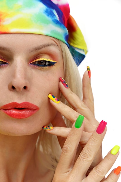 Une fille dans un foulard avec une manucure et un maquillage multicolores