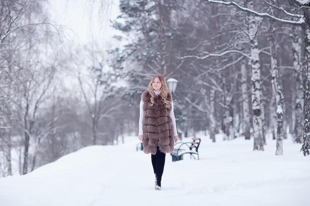 fille dans un gilet de fourrure marche en hiver à l'extérieur / jeune modèle adulte en fourrure de vêtements d'hiver