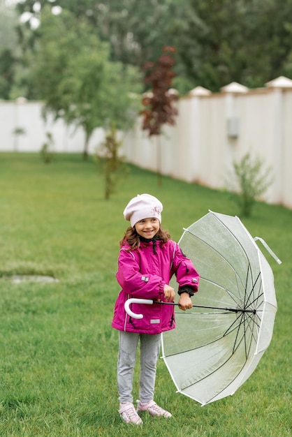 une fille dans un imperméable rose vif avec un parapluie transparent