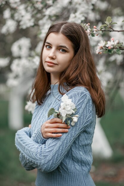 Fille dans un jardin fleuri dans une veste bleue