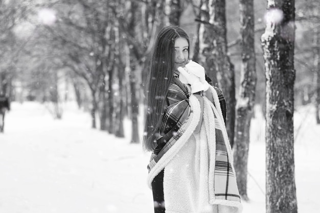 Une fille dans un jour nuageux d'hiver de champs et de forêts enneigés