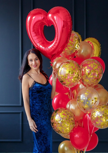 une fille dans une longue robe bleue avec des boules en forme de coeur rouge et or