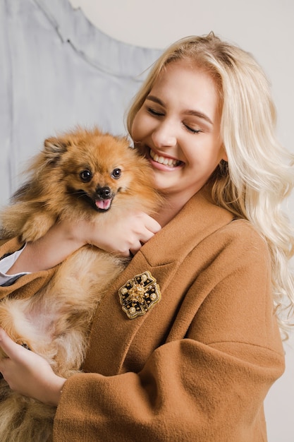 Fille dans un manteau avec une broche embrasse un chien de race spitz poméranien