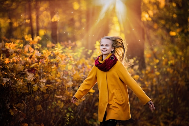 fille dans un manteau jaune vif fonctionnant dans le parc