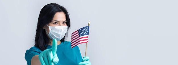 Une fille dans un masque médical et des gants tient un drapeau américain dans ses mains Concept de coronavirus Protégez votre santé xAStop à la menace d'une pandémie